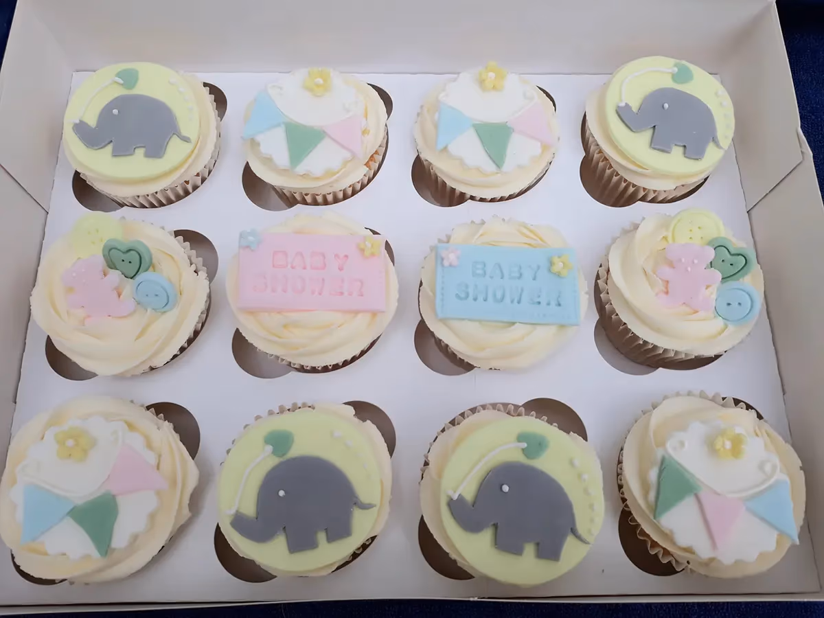 Assorted baby shower cupcakes with pastel designs by Thelwall Bakehouse