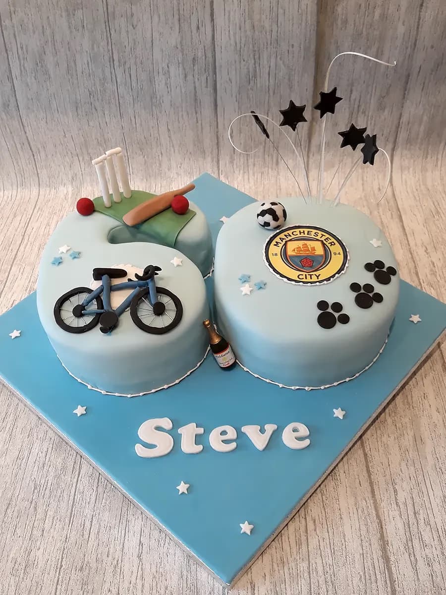 A light blue 60th birthday cake shaped like the number 60, decorated with a cricket set, a bicycle, a Manchester City FC logo, black paw prints, stars, and a miniature champagne bottle, with the name 'Steve' in white letters on the cake board.