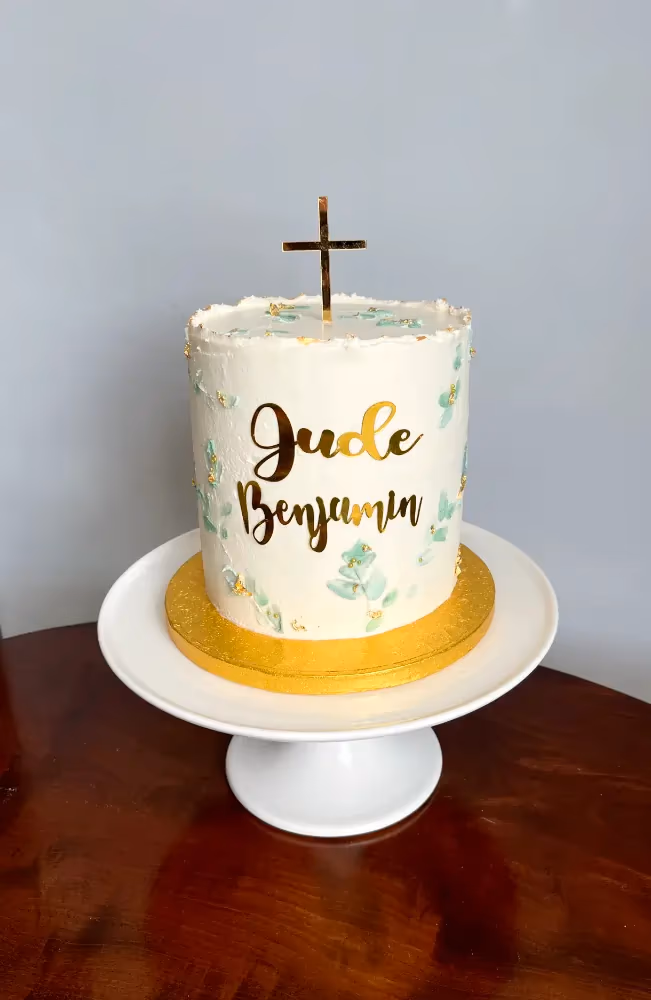 Single-tier white christening cake with green and gold cross topper