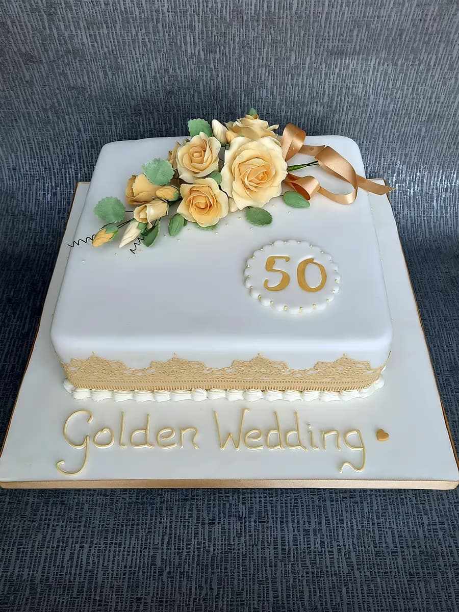 Square golden wedding anniversary cake with white fondant and gold flowers marking 50 years