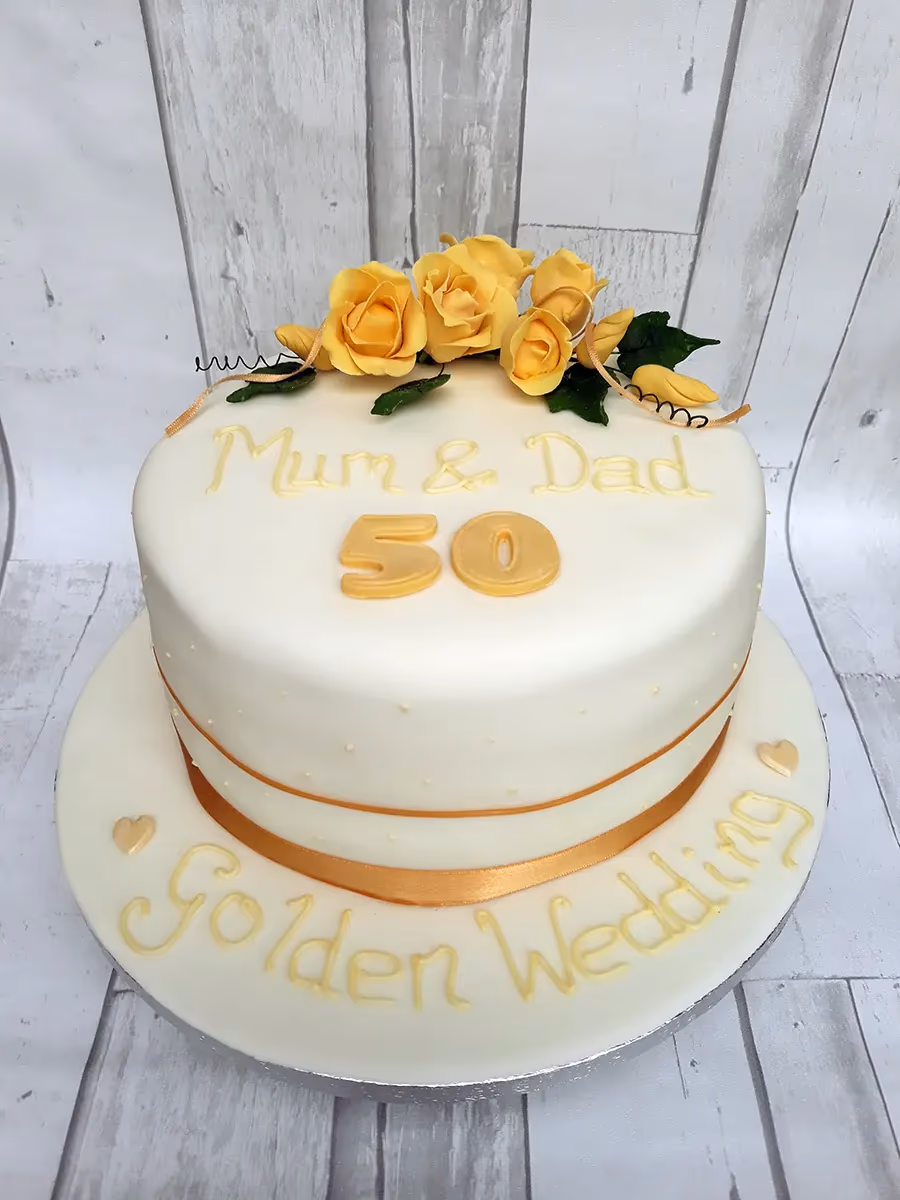 Golden wedding anniversary cake with white fondant and yellow roses marking 50 years