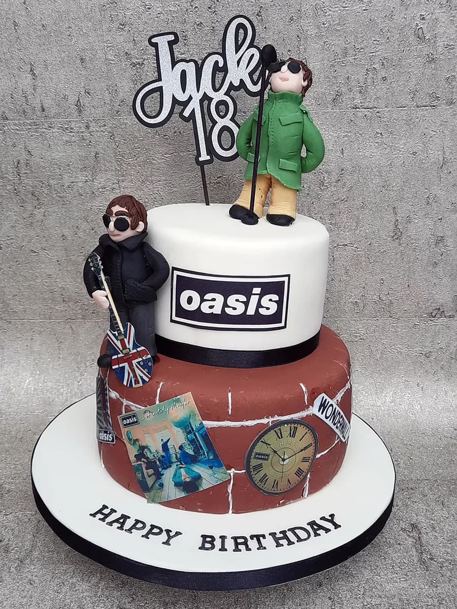 A two-tier birthday cake with an Oasis band theme, featuring fondant figures resembling Liam and Noel Gallagher, the Oasis logo, album artwork, a clock, and a 'Jack 18' cake topper, with 'Happy Birthday' written on the cake board.