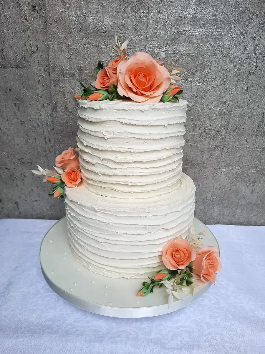 Two-tier white textured buttercream cake with peach roses