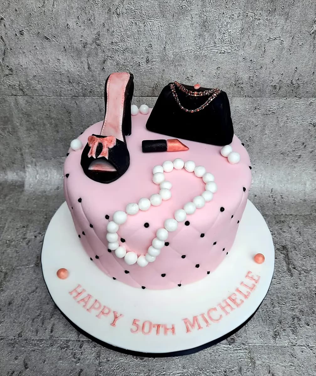 50th birthday cake with pink quilted fondant, high heel, handbag, pearls, and lipstick decoration