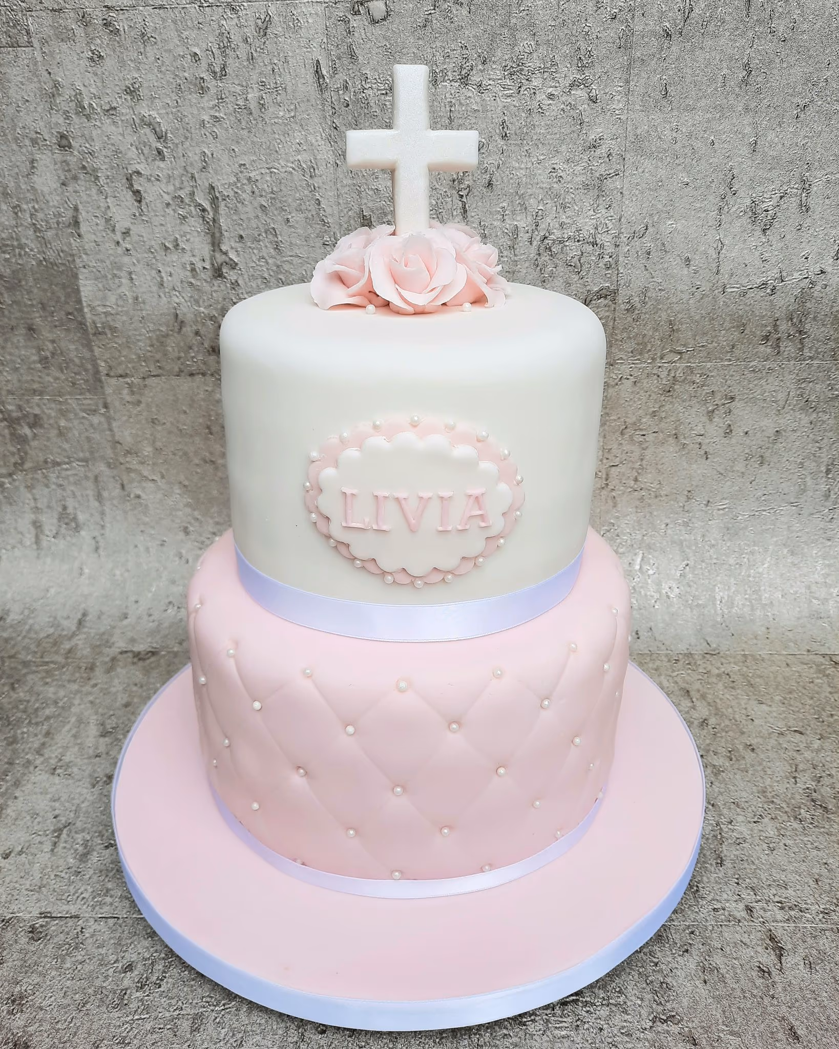 Girl's two-tier pink and white christening cake with cross and roses