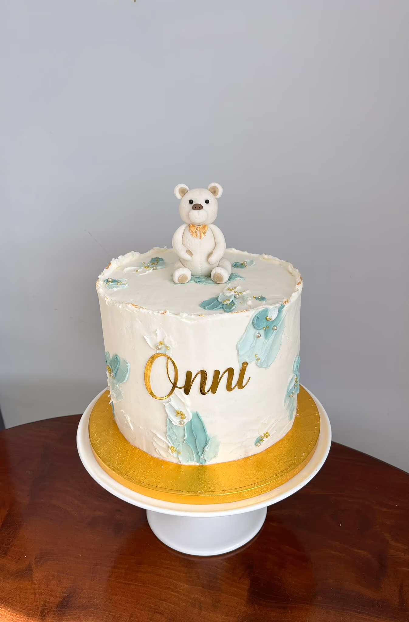 Christening cake with teddy bear in white green and gold