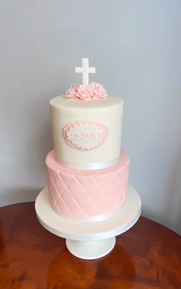 Two-tier pink and white quilted christening cake with cross and roses