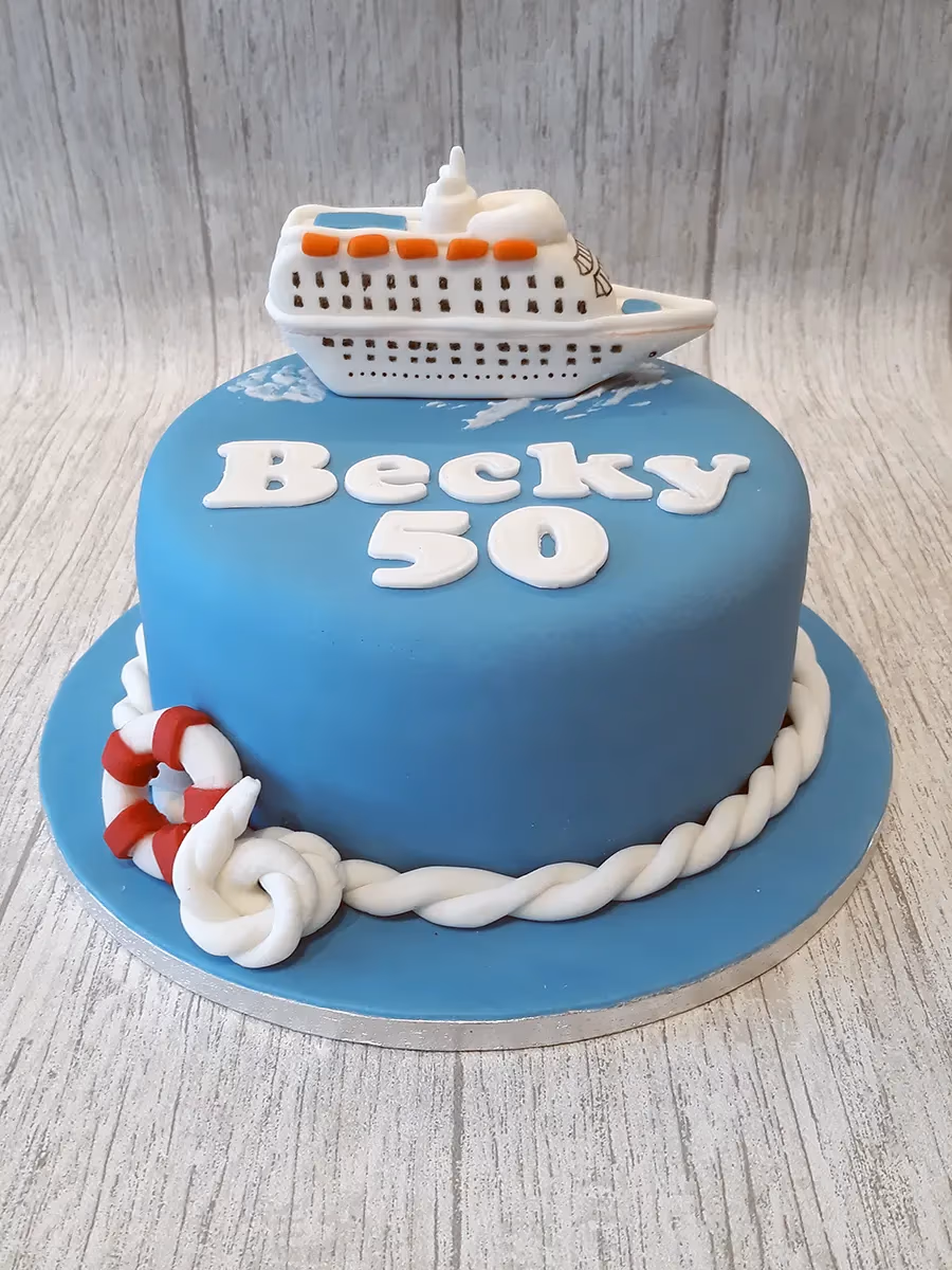 50th birthday cake shaped as a cruise ship with nautical blue and lifebuoy decoration