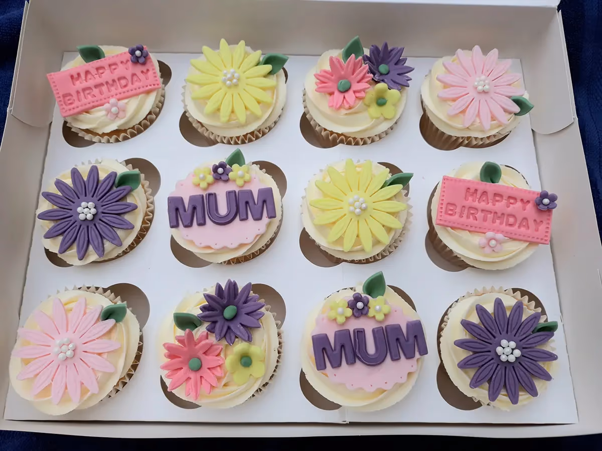 Assorted birthday cupcakes with floral decorations by Thelwall Bakehouse