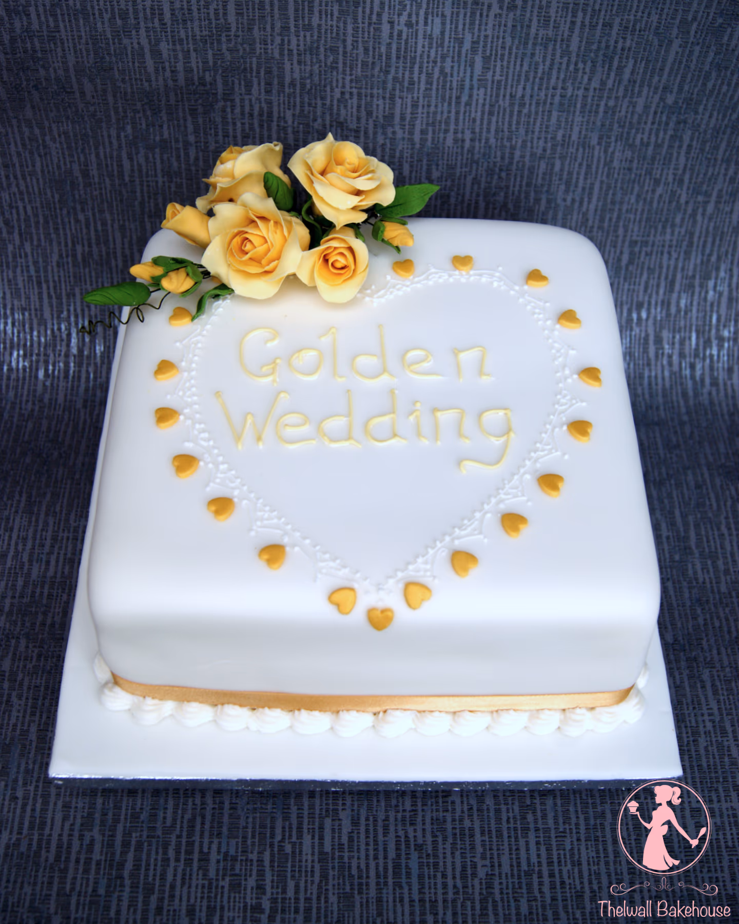 Square golden wedding cake with white fondant, yellow roses and gold hearts