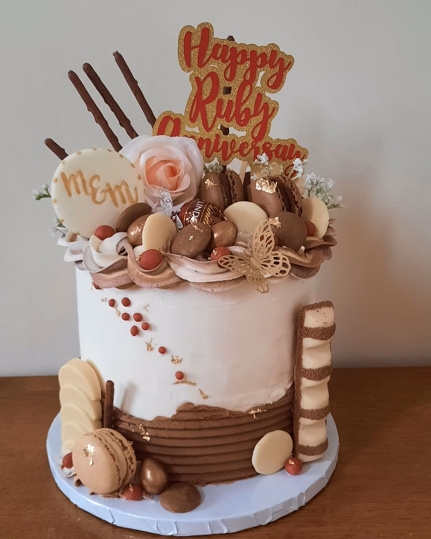 Ruby anniversary cake with white chocolate, macarons and gold decoration