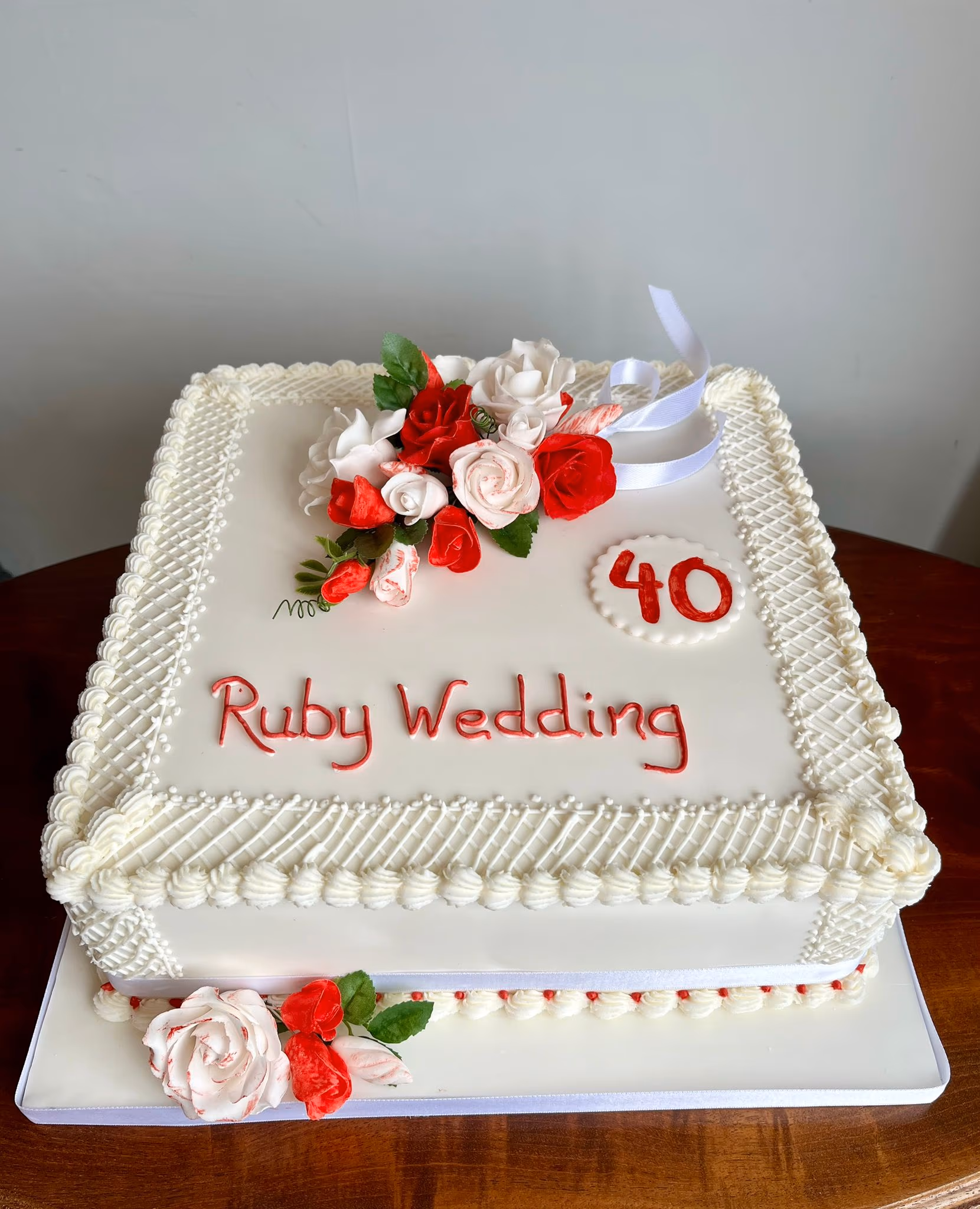Two-tier square ruby wedding anniversary cake with red and white flowers marking 40 years