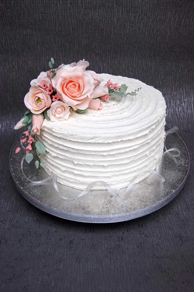 Single-tier white buttercream wedding cake with pink sugar roses