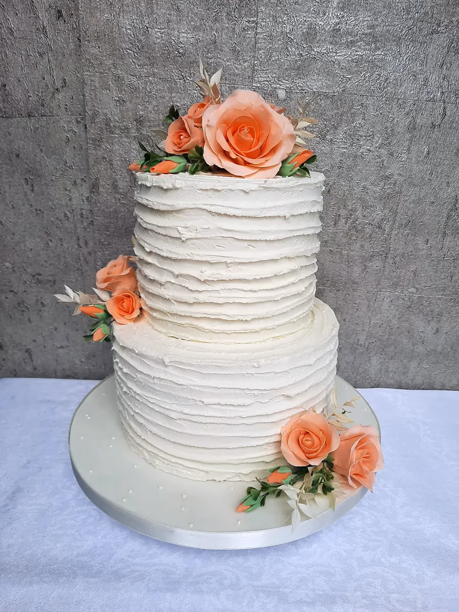 Two-tier white textured buttercream cake with peach roses