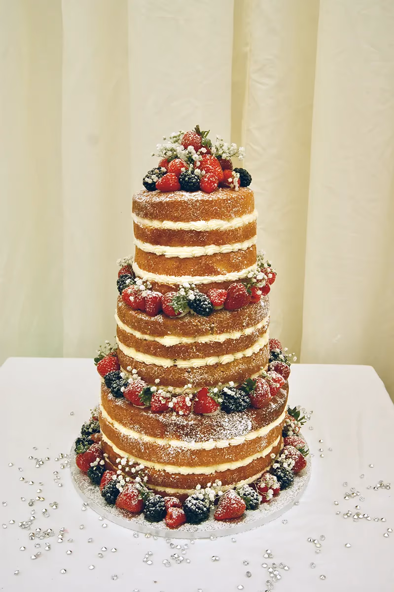 Four-tier naked wedding cake with mixed berries and baby's breath