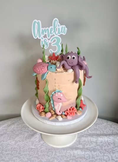 An under the sea 3rd birthday cake for Amelia with a sugar octopus, turtle and seahorse, coral and seaweed, and an 'Amelia is 3' topper.