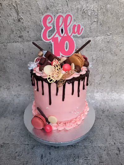 Pink drip cake for a 10th birthday with chocolates, macarons and sweets