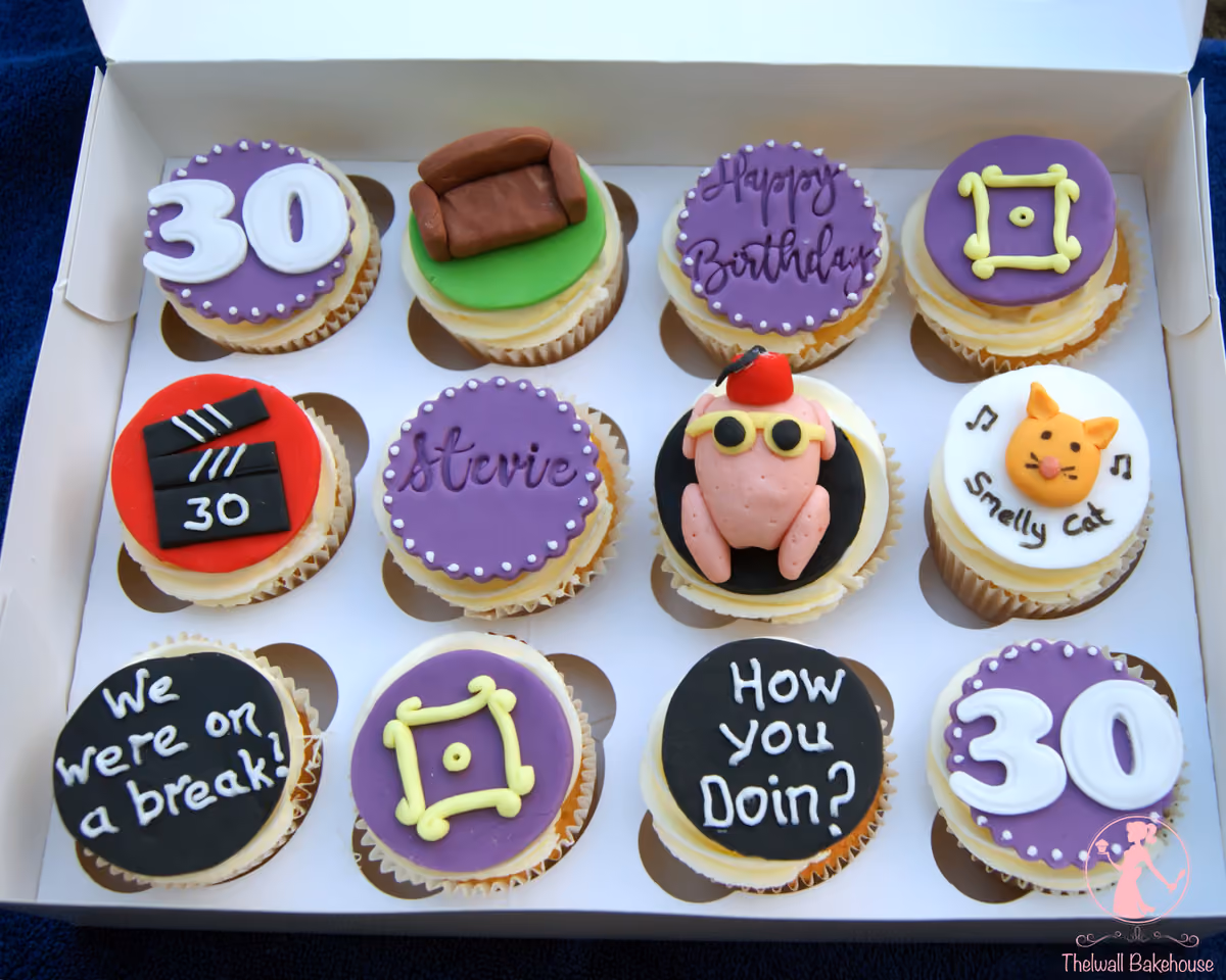 A dozen cupcakes in a white box, decorated with various Friends TV show themes and 30th birthday elements. Designs include the iconic purple door frame, Central Perk couch, a turkey wearing a fez, a clapperboard with '30', a cat face with 'Smelly Cat', and text such as 'Happy Birthday', 'Stevie', 'We were on a break!', 'How you doin?', and '30'.
