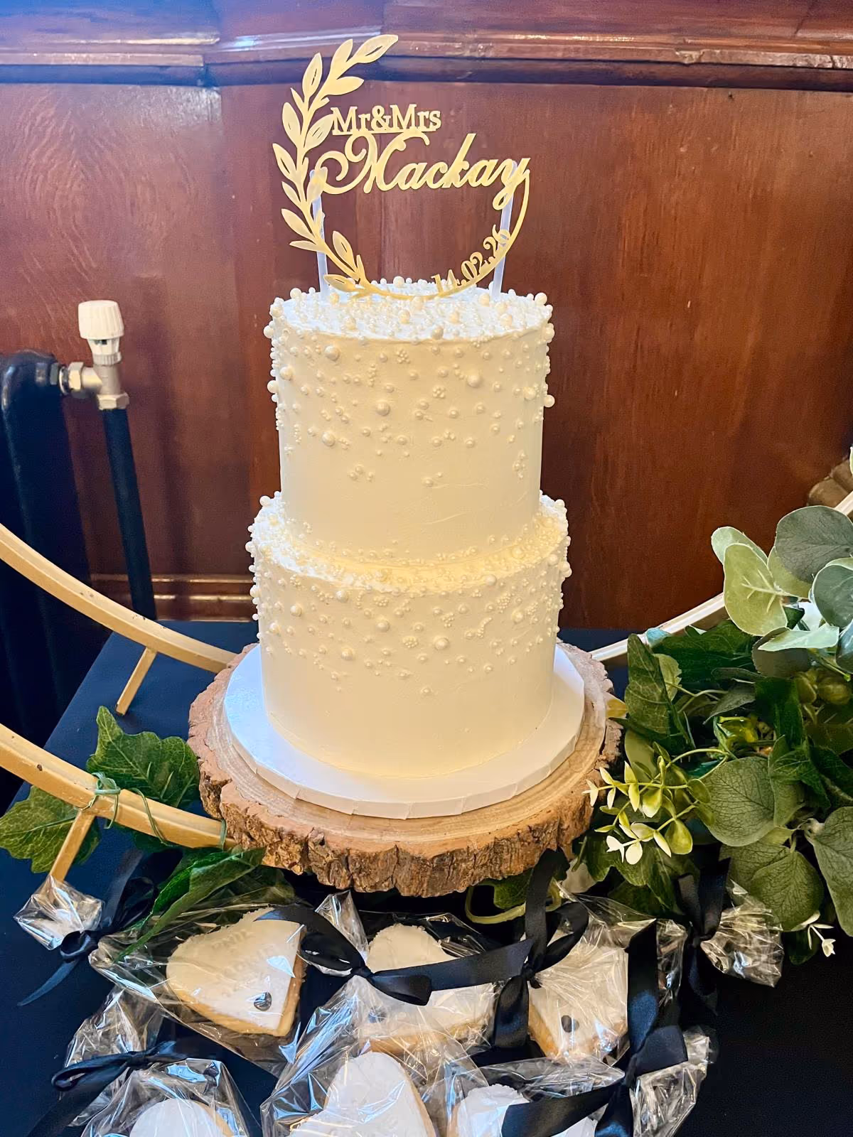 Two-tier white wedding cake with pearls and matching heart biscuit favours